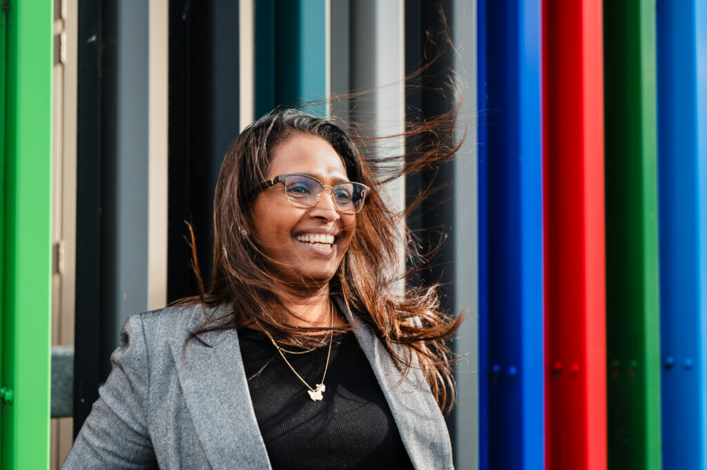 A woman is smiling and looking into the distance with her hair swept by the wind