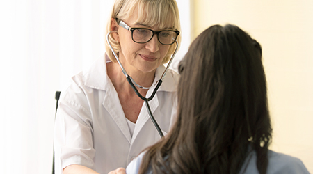 Photo of a doctor listening to a patient's heart with a stethoscope