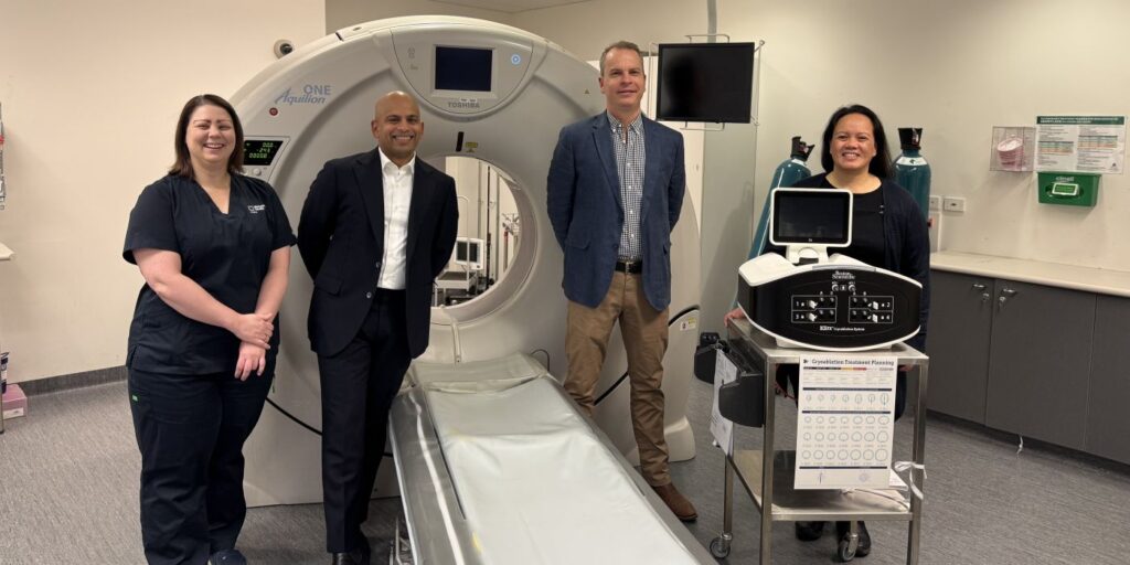 Photo of clinicians standing around a CT scan bed