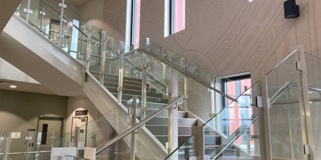 A modern staircase filled with natural light and Aboriginal artwork on the wall