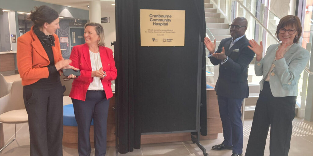 Four people stand in front of a plaque that reads Cranbourne Community Hospital.