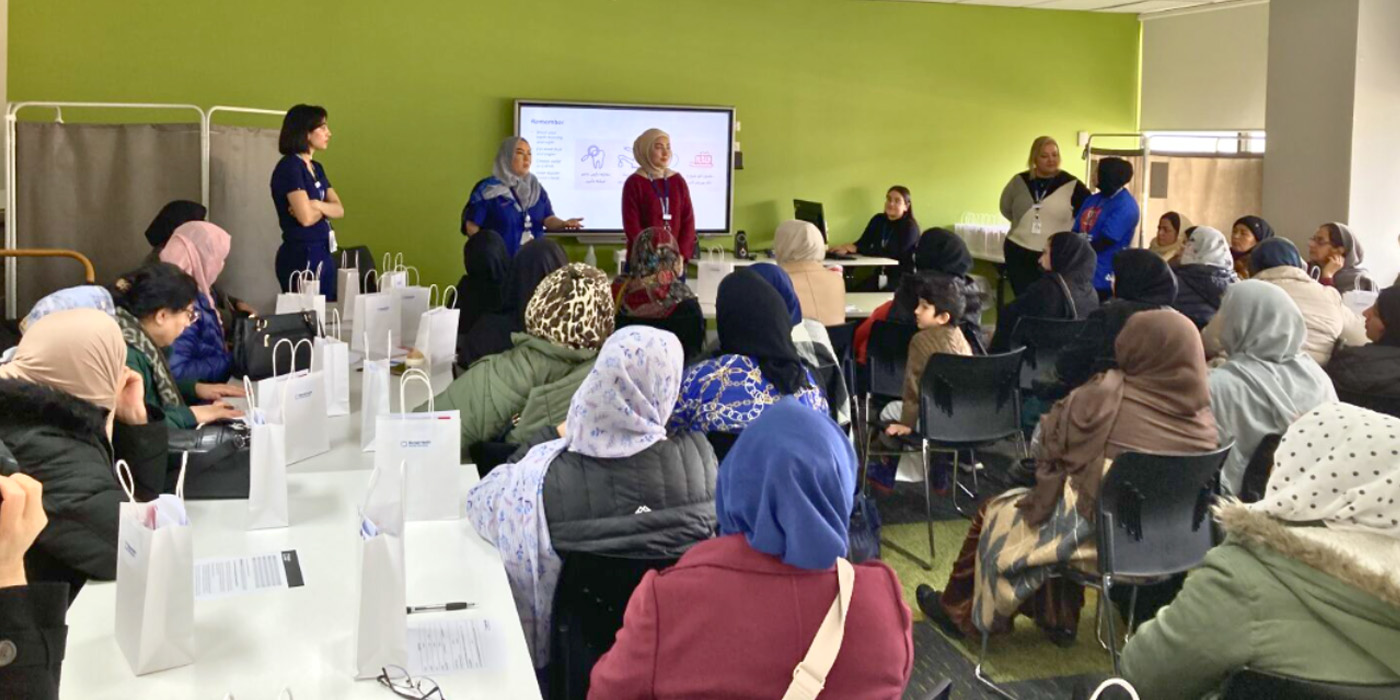 Two women are presenting to a room of seated women from the Afghan Women’s Organisation Victoria