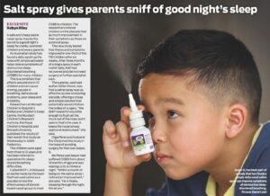 Child holding a nasal spray bottle near their nose with a Herald Sun newspaper article about salt spray and sleep benefits.