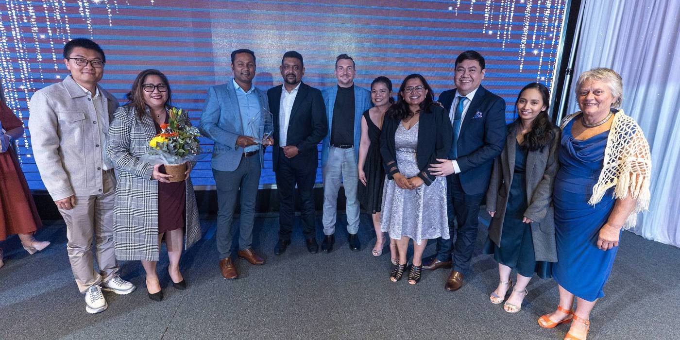 Ten people smiling dressed in formal attire, one person holding flowers