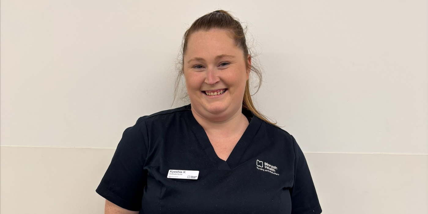 Kyeshia wears a navy blue v-neck scrub top and smiles at the camera