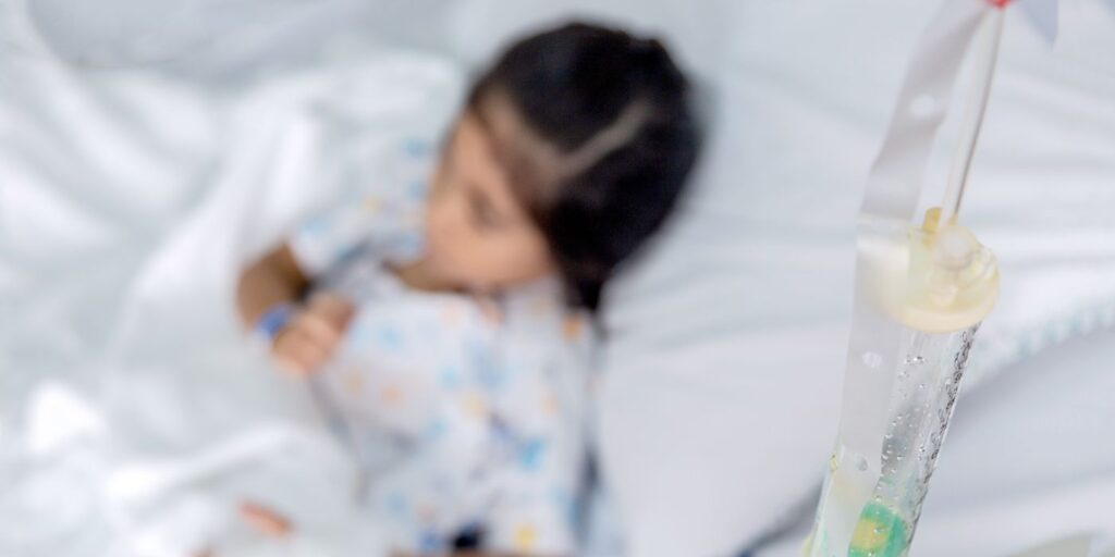 Child lying in a hospital bed with an IV drip nearby