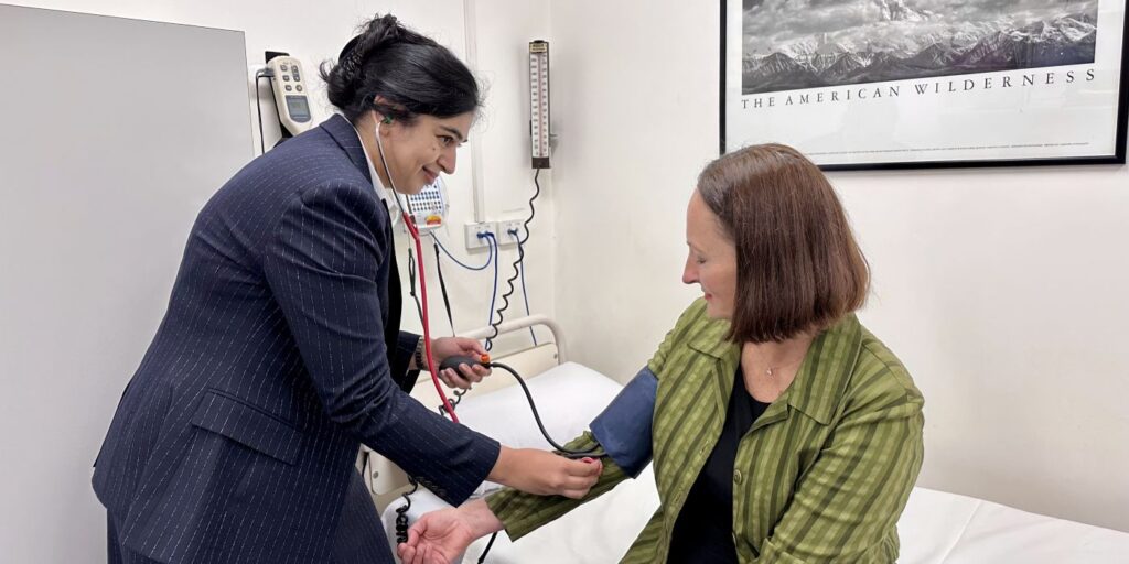 A female doctor checking the blood pressure of a female stroke patient in her 50s in a consultation room.