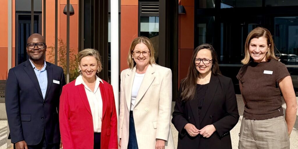 Five individuals posing in front of the Cranbourne Community Hospital.