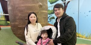 17-month-old Alina in her pram with her mum and dad beside her. Alina received stems cells from donated cord  blood as part of the ALLO trial.
