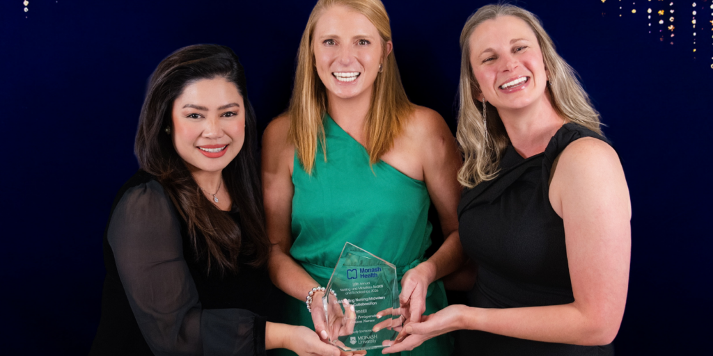 NAMAS Team of the Year are holding a glass award against a dark blue background with sparkling lights
